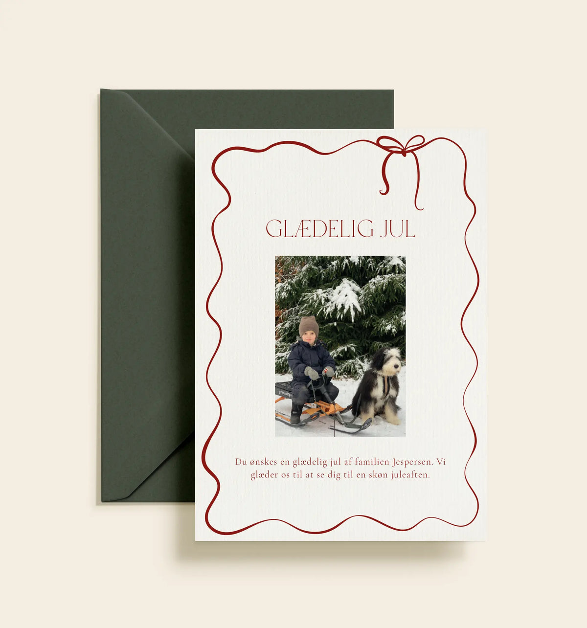 Personligt julekort med familiefoto, rød bølget ramme og sløjfe samt teksten “Glædelig jul”.